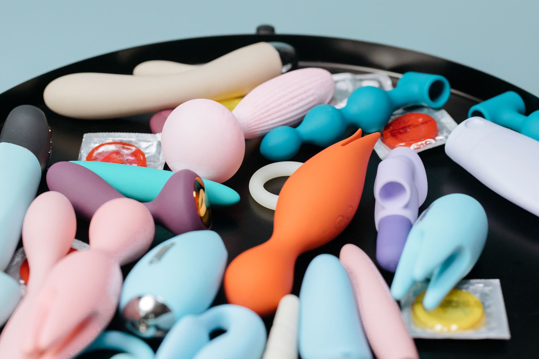A collection of lemon sexual toys in various colors arranged on a black surface, representing accessible pleasure options