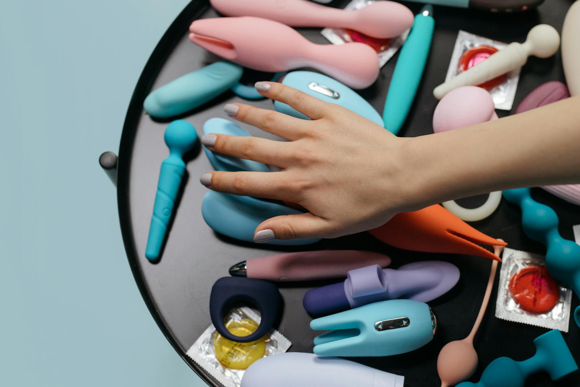 A hand holding a lemon clitoral vibrator against a minimalist purple backdrop