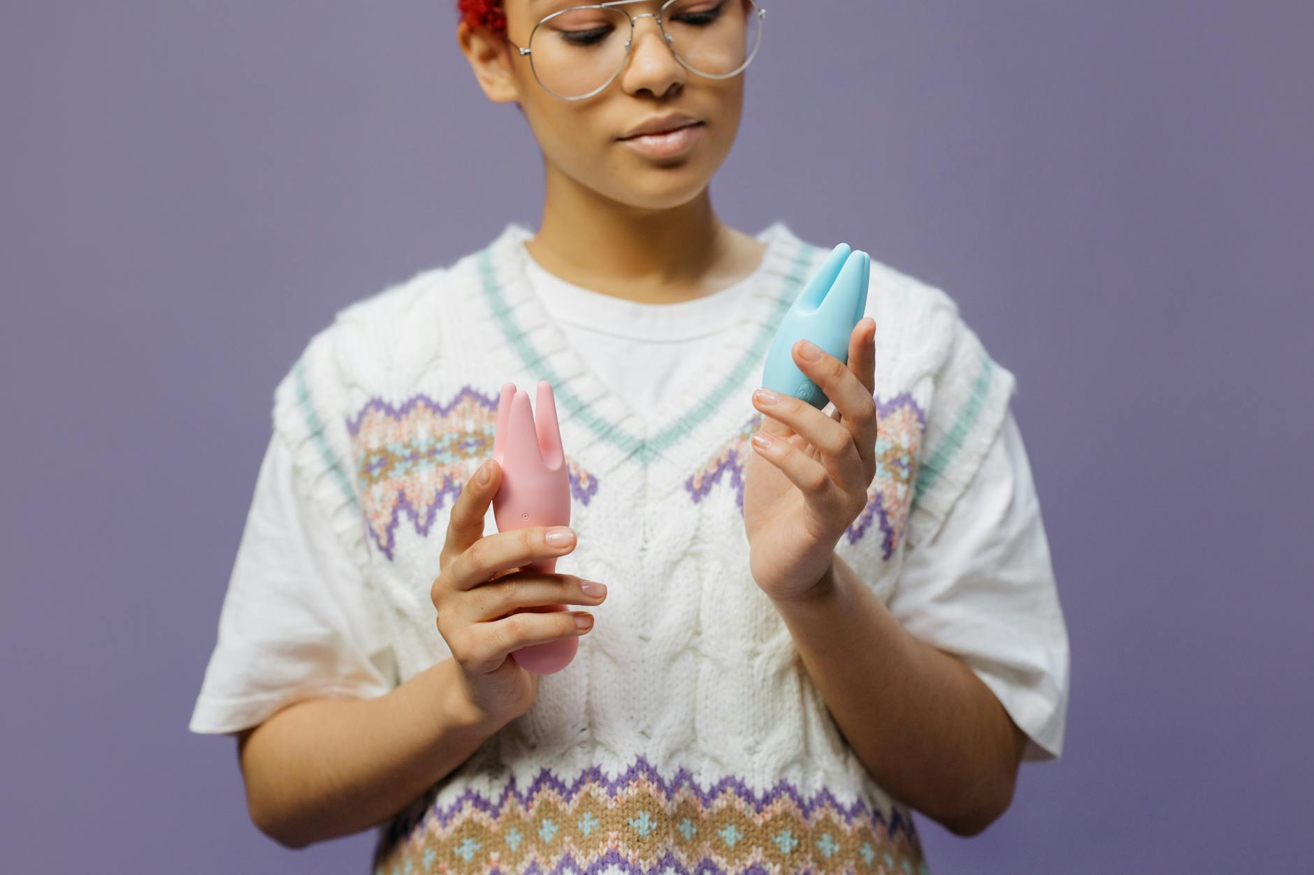 Woman holding two silicone vibrators in a thoughtful pose, representing intimacy options for couples