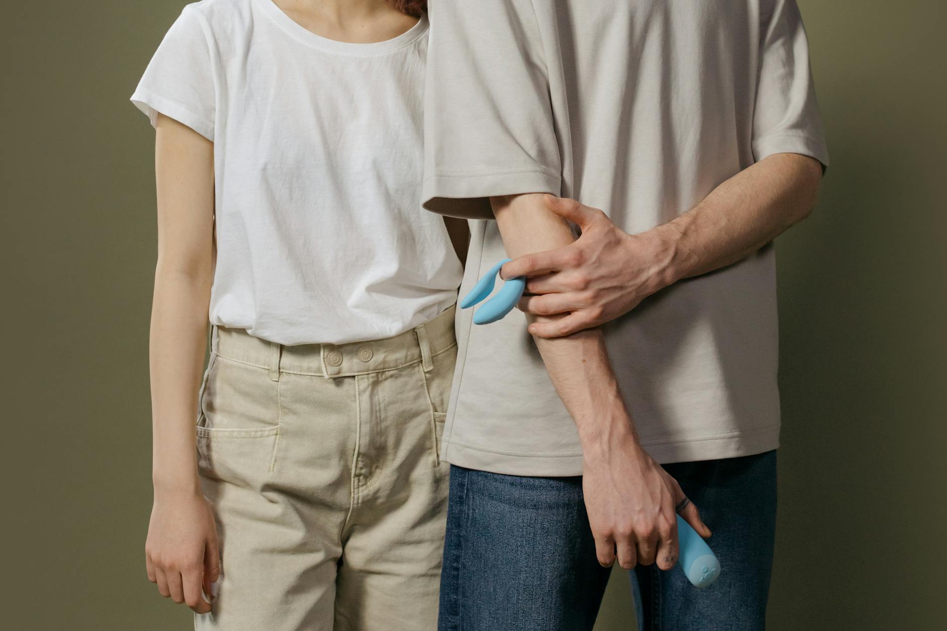 A hand holding an orange vibrator against a purple backdrop, showcasing suction-based clitoral stimulation design